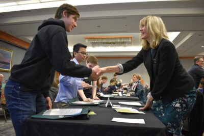 Two people shaking hands at an exhibit table